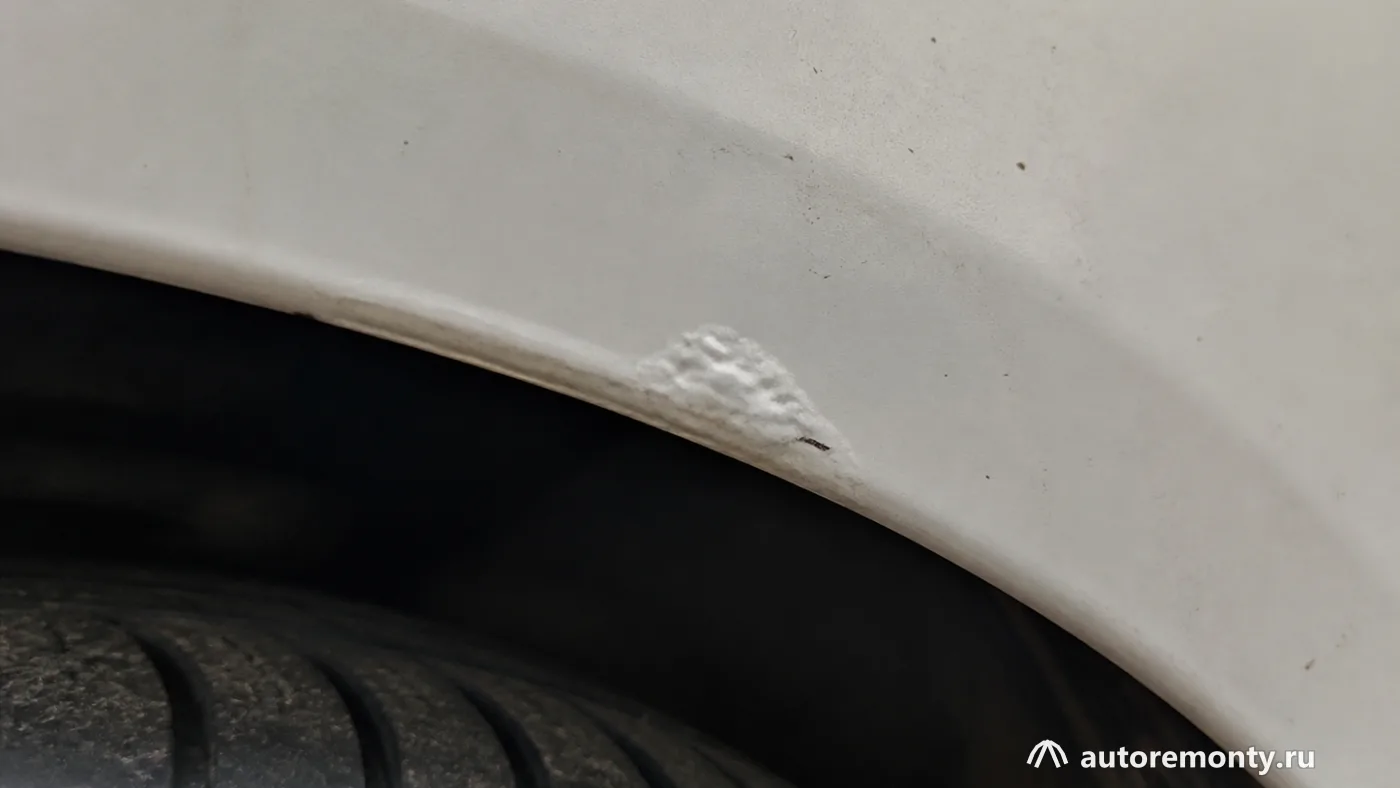 Нижней кромки задней колёсной арки Lada Vesta с небольшим вздутием лакокрасочного покрытия; рядом видна — болячки лада веста 2018 кузов ржавчина