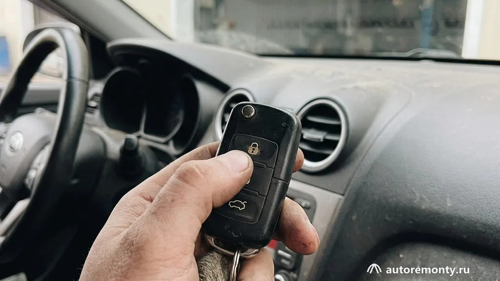 Брелка сигнализации в руке человека на фоне приборной панели Kia Rio, водитель нажимает на кнопку — не работает центральный замок