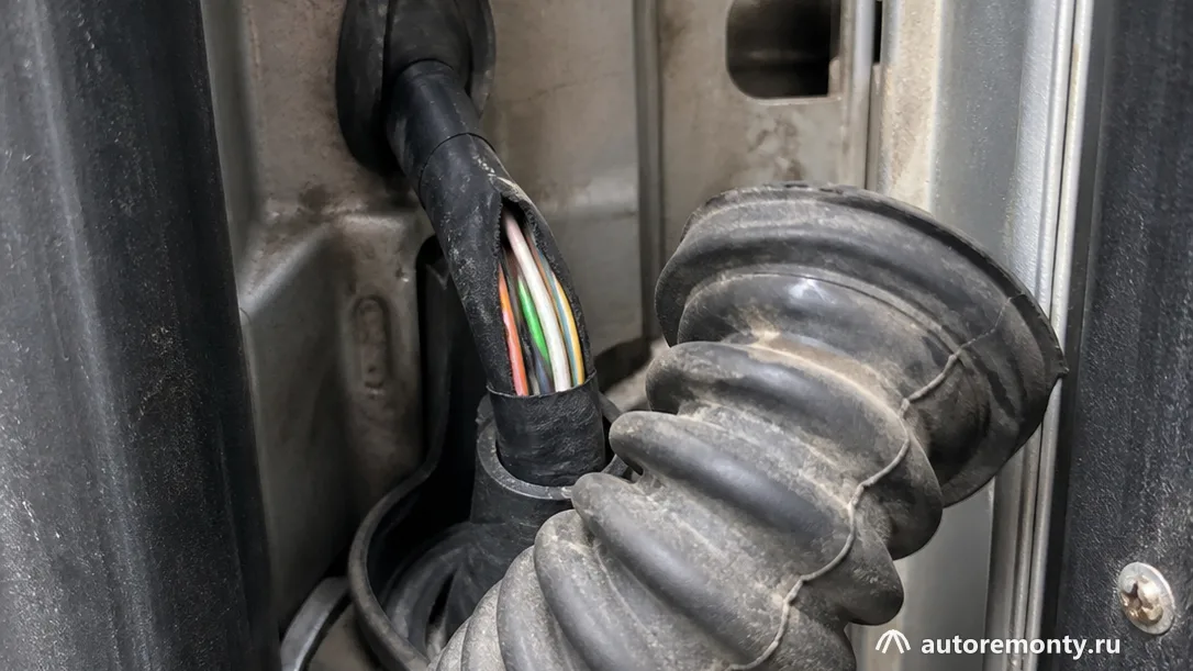 Резиновой гофры между передней дверью и стойкой кузова, гофра отведена в сторону, виден дверной жгут с — обрыв проводов в двери